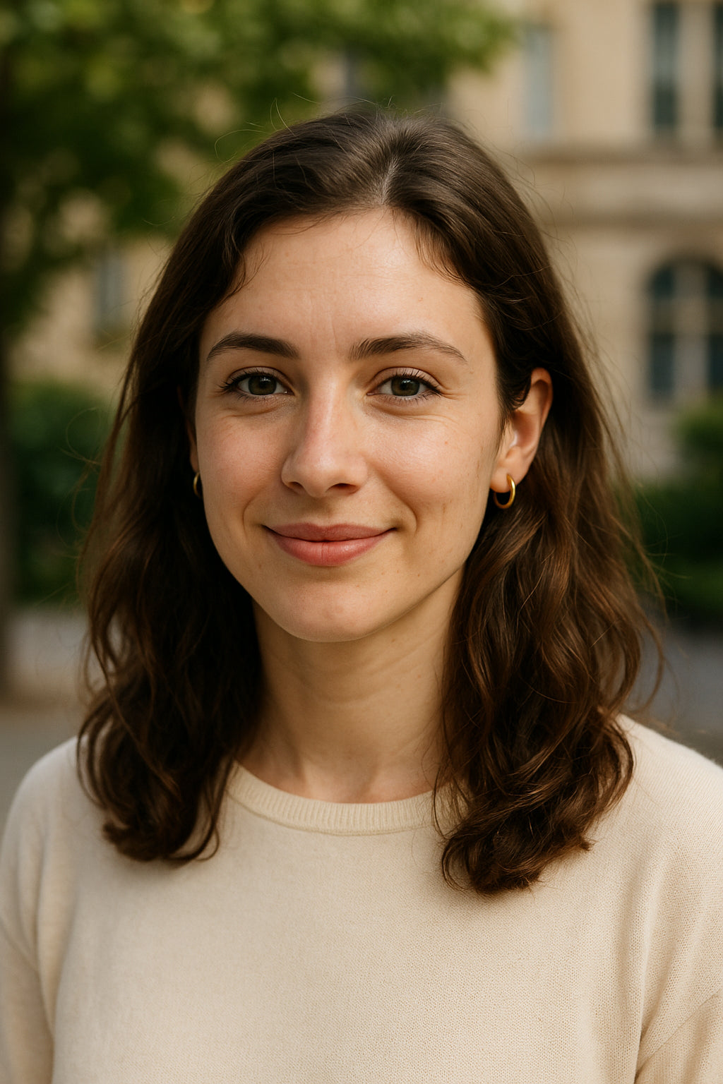 Woman with shoulder-length brown hair wearing a beige sweater outdoors.